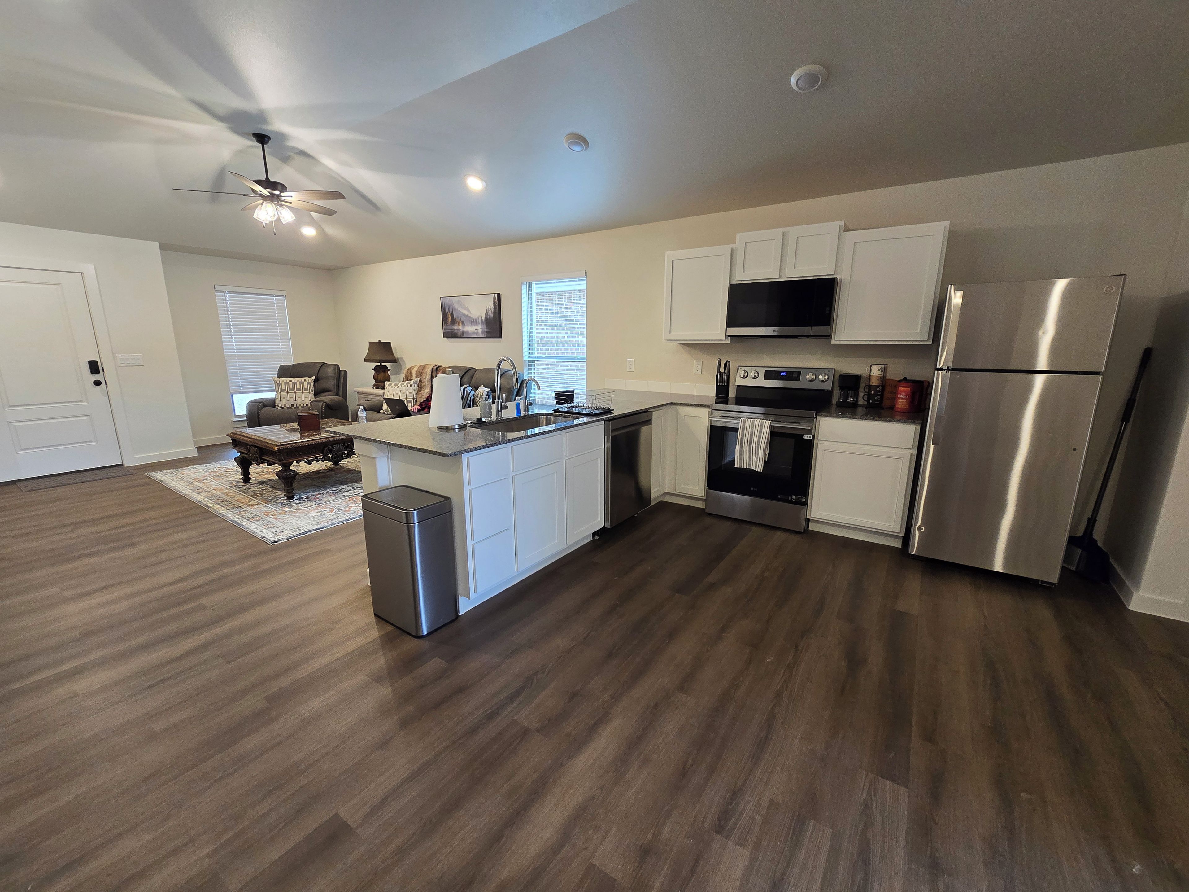 A modern kitchen with white cabinets, stainless steel appliances, and a central island.