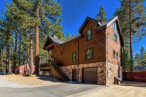 A two-story log cabin with a stone foundation, a front porch, and a garage. - Lake & Après Chalet BBQ, Games, Pool Table (South Lake Tahoe)