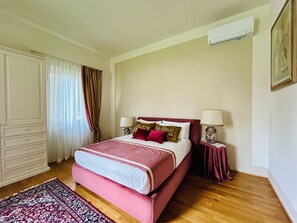 A bedroom with a bed, two bedside tables with lamps, a wardrobe, and a window with curtains. - Le Falene Guest House (Comeana)