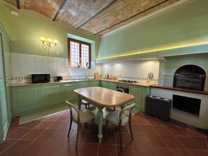 A kitchen with green cabinets, a wooden table, and a built-in oven. - Le Falene Guest House (Comeana)