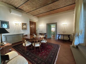 A dining area with a wooden table and chairs, a patterned rug, and a radiator. - Le Falene Guest House (Comeana)