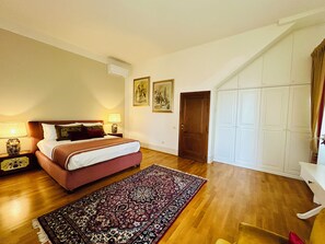A bedroom with a bed, bedside lamps, a rug, a wardrobe, and a door. - Le Falene Guest House (Comeana)