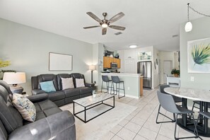 A modern living room with a sofa, coffee table, and a ceiling fan. - 3BR/3BA Kissimmee Townhome, Private Pool, Near Disney (Kissimmee)