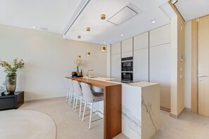 Cozinha moderna com bancada de mármore, forno embutido e espaço para bancos.