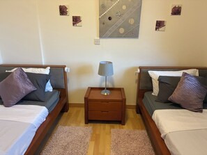 A hotel room with two beds, a nightstand with a lamp, and a wall art piece. - 🏡 Modern & Charming spacious 2 bedroom apartment in popular Polis Gardens (Poli Chrysochous)