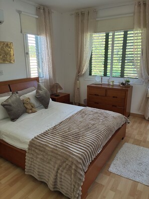 A bedroom with a bed, bedside table, dresser, and a window with curtains. - 🏡 Modern & Charming spacious 2 bedroom apartment in popular Polis Gardens (Poli Chrysochous)
