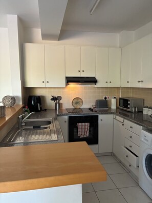 A kitchen with white cabinets, a built-in oven, a microwave, a coffee maker, and a washing machine. - 🏡 Modern & Charming spacious 2 bedroom apartment in popular Polis Gardens (Poli Chrysochous)