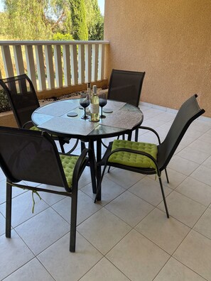 A round table with four chairs, a bottle of white wine, and two glasses on a balcony with a white railing. - 🏡 Modern & Charming spacious 2 bedroom apartment in popular Polis Gardens (Poli Chrysochous)