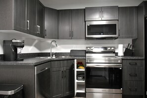 Una cocina moderna con armarios de madera oscura, electrodomésticos de acero inoxidable y un horno empotrado.