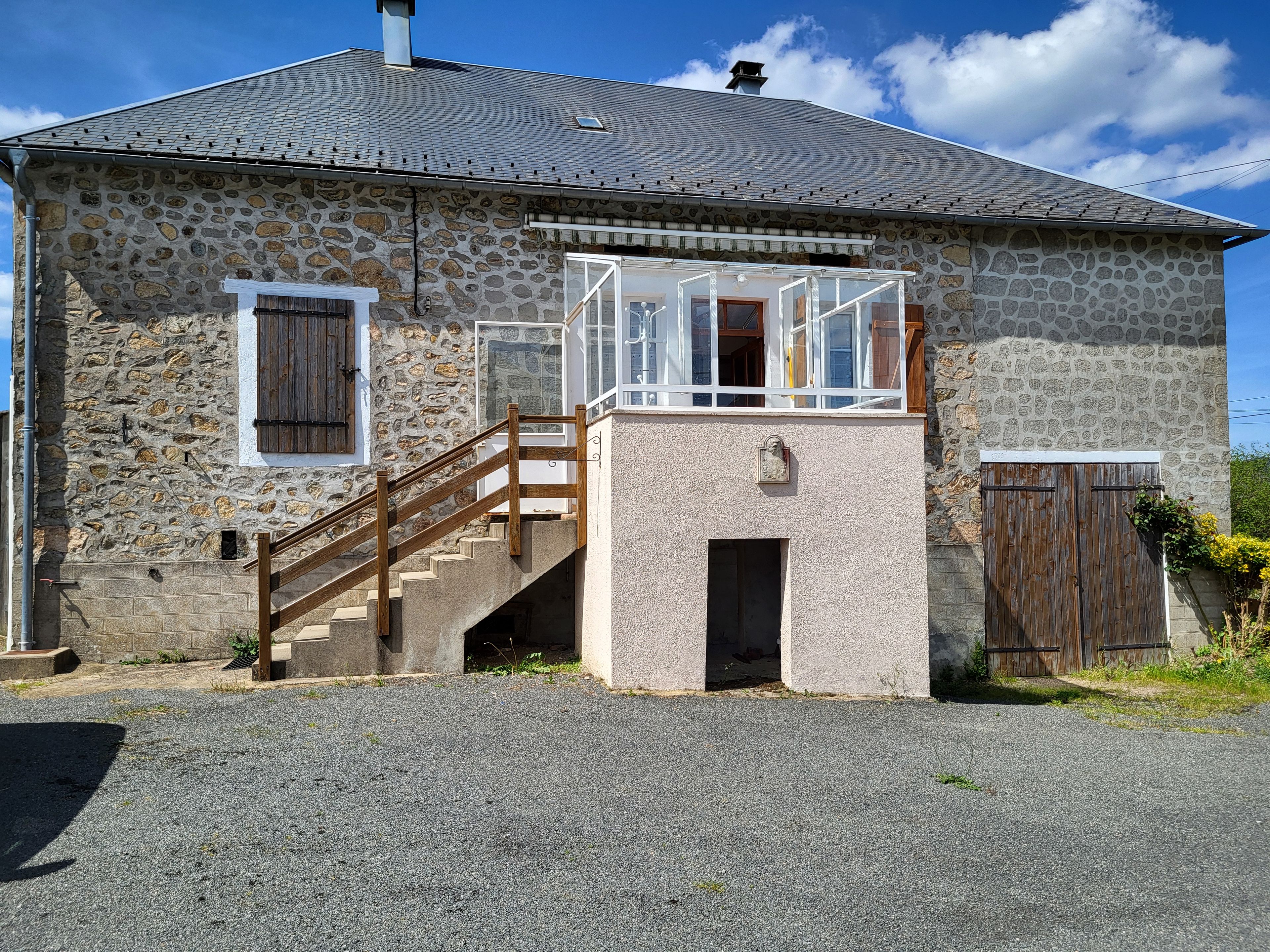 A stone building with a wooden staircase leading to a balcony.