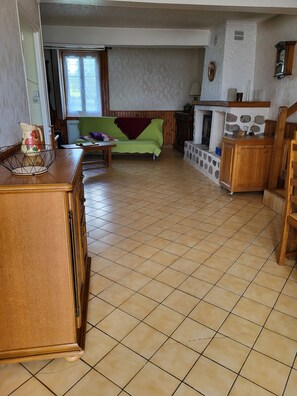 A living room with a sofa, a wooden cabinet, and a tiled floor. - Vacation Home (Château-Chinon (Campagne))