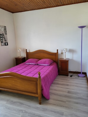 A bedroom with a wooden bed, a purple bedspread, two bedside tables with lamps, and a floor lamp. - Vacation Home (Château-Chinon (Campagne))
