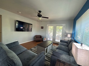 A living room with a ceiling fan, a flat-screen TV mounted on the wall, a coffee table, and a sofa set. - 6 Bell Rock Villas Condo W/Red Rock View + Hot Tub (Sedona)
