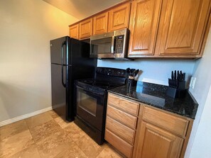 A kitchen with wooden cabinets, a black refrigerator, a microwave, an oven, and a countertop with knives. - 6 Bell Rock Villas Condo W/Red Rock View + Hot Tub (Sedona)