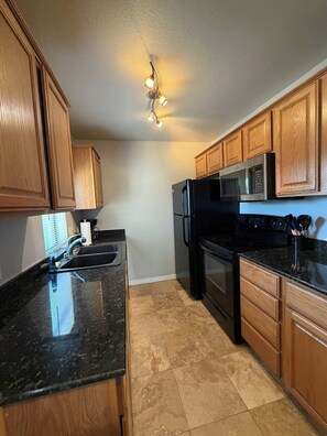A kitchen with wooden cabinets, a black countertop, a stainless steel refrigerator, a microwave, and an oven. - 6 Bell Rock Villas Condo W/Red Rock View + Hot Tub (Sedona)