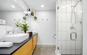 A modern bathroom with a white sink, wooden cabinets, a mirror, and a shower with a handheld showerhead. - Unique wedge house 1.5 miles from historic district. Amazing for families! (St. Augustine)