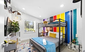 Ein modernes Schlafzimmer mit Etagenbetten, einem Schreibtisch und einer farbenfrohen Wand.