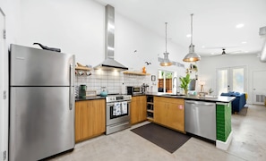A modern kitchen with stainless steel appliances, wooden cabinets, and pendant lighting. - Unique wedge house 1.5 miles from historic district. Amazing for families! (St. Augustine)
