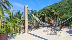 A hammock on a terrace with a view of palm trees and a mountain. - Lovely 1-bedroom house, steps from the beach and restaurants, with beach views. (Yelapa)