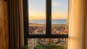 Una ventana con vistas a un pueblo costero y una playa al atardecer.