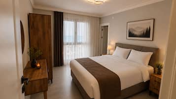 A hotel room with a large bed, bedside tables, a wooden wardrobe, a window with curtains, and a framed picture on the wall.
