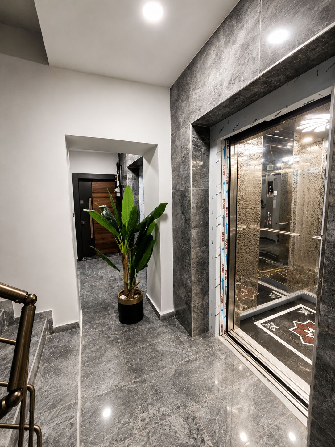 Un interno moderno con pavimento in marmo, una pianta in vaso e un ascensore.