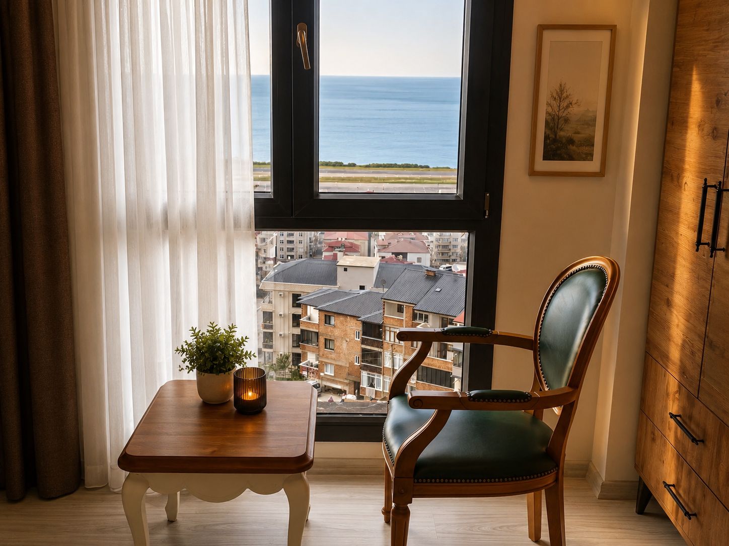 Una stanza con vista mare, una sedia di legno, un tavolino con una pianta e un armadio.
