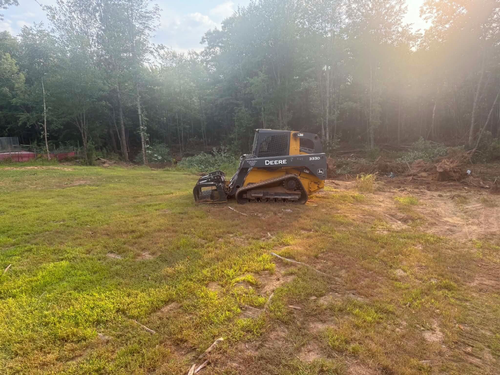 A construction vehicle in a grassy area with trees in the background.
