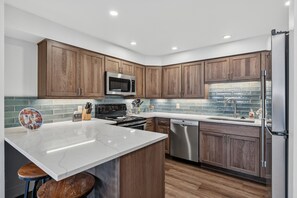 A modern kitchen with wooden cabinets, stainless steel appliances, and a marble countertop. - Walk to Lifts & Main St | Hot Tub (Breckenridge)