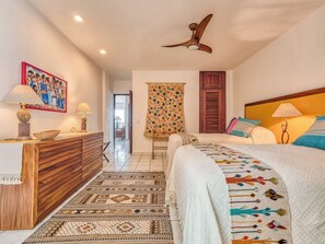 A hotel room with a bed, a desk, a chair, a ceiling fan, a window, and a door. - Cozy Mexican-style oceanfront apartment located 5 minutes away from Puerto Vallarta's main area. (Puerto Vallarta)