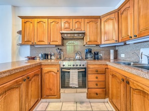 A kitchen with wooden cabinets, a stainless steel stove, and a sink. - Cozy Mexican-style oceanfront apartment located 5 minutes away from Puerto Vallarta's main area. (Puerto Vallarta)