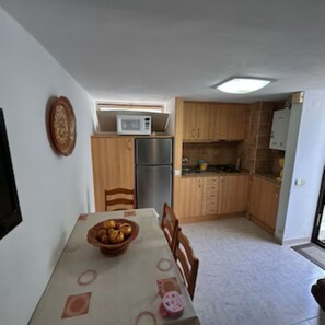 A compact kitchen with wooden cabinets, a refrigerator, and a microwave. - Apartment near Falésia Beach (Albufeira)