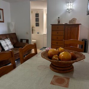 A dining area with a table set for two, a wooden cabinet, and a wall-mounted light fixture. - Apartment near Falésia Beach (Albufeira)