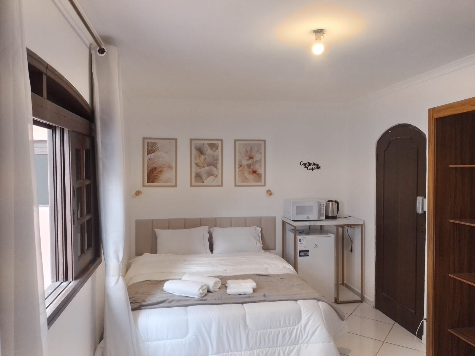 Une chambre à coucher avec un lit, une table de chevet sur laquelle se trouve un micro-ondes, et une porte.