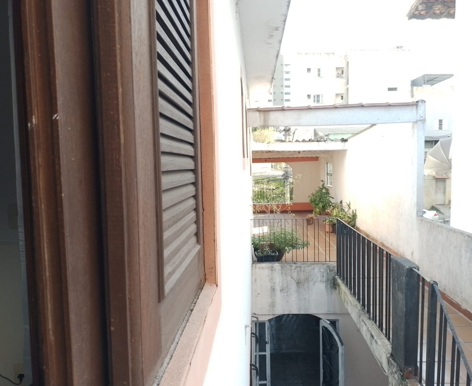A balcony with a metal railing, a potted plant, and a view of a building in the background.