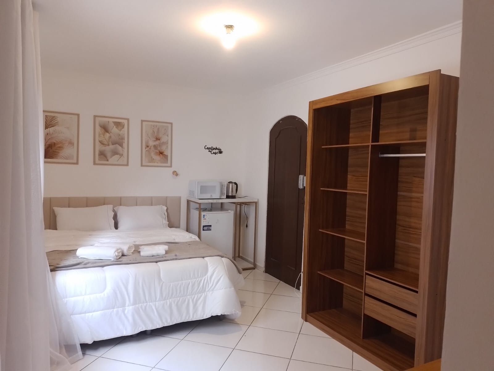 Une chambre d’hôtel comprenant un lit, une table de chevet avec un micro-ondes, une armoire et des œuvres d’art murales.