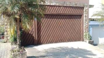 A two-story house with a garage door, a palm tree, and a stone wall.