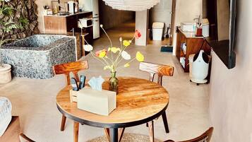 A modern living room with a round wooden table, leather chairs, and a hanging light fixture.