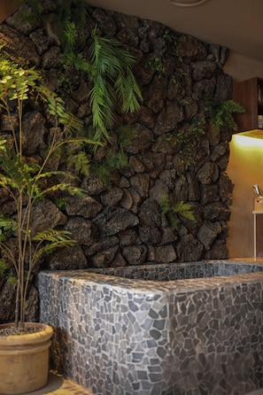 A stone wall with greenery and a tiled bench area. - Lumiere (Busan)
