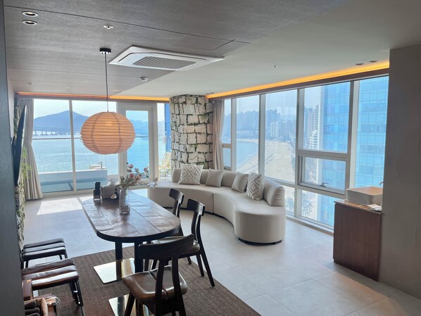 Un interior moderno con comedor, asientos y un gran ventanal con vista a la ciudad.