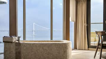 Une salle de bain moderne avec un lavabo en pierre, de grandes fenêtres et une vue sur un pont.