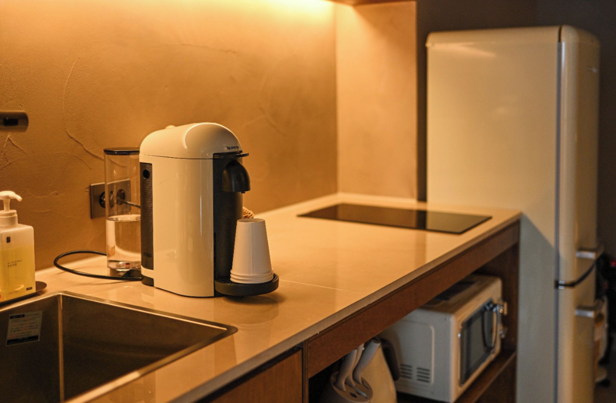 Een kitchenette met een koffiezetapparaat, een magnetron en een koelkast.