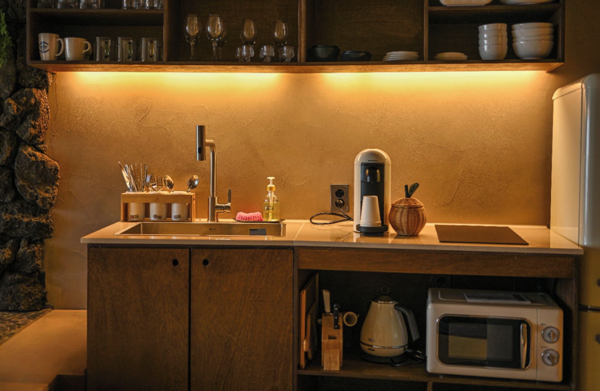 A compact kitchen with a built-in microwave, a coffee maker, and a sink.