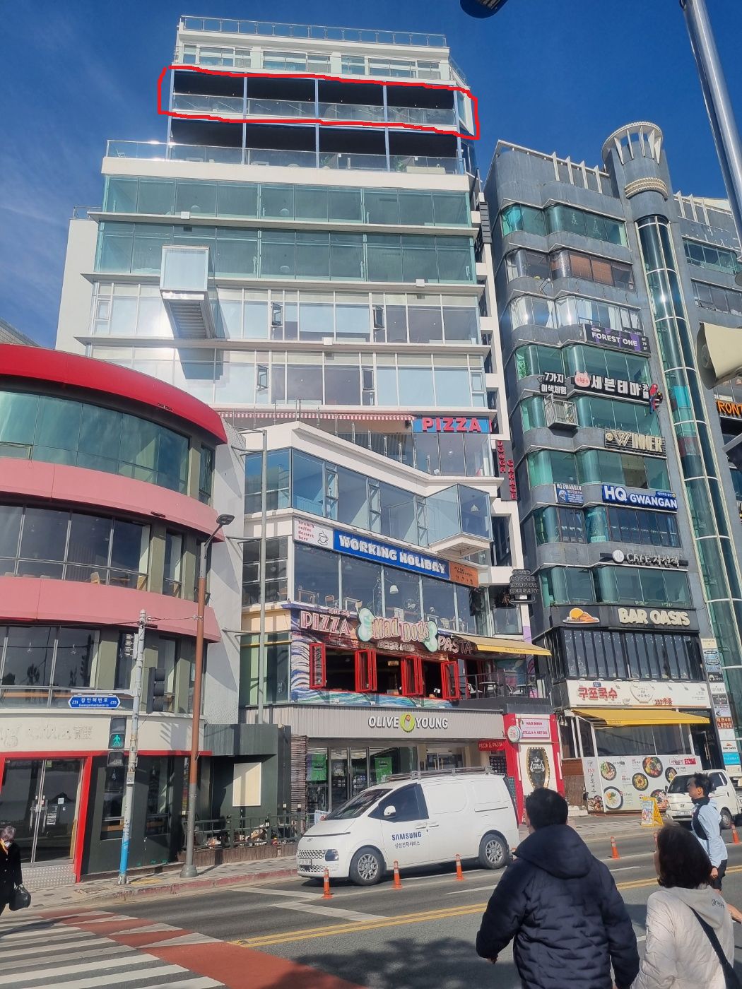 Un edificio comercial de varios pisos con diversas tiendas, incluyendo una pizzería y una cafetería.