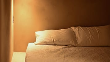 A room with a bed, a hanging light fixture, and a window.
