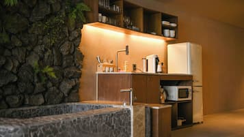 A kitchen with a stone wall, a sink, a microwave, and a refrigerator.