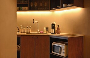 Una cocina compacta equipada con microondas, cafetera y lavabo.