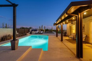 A swimming pool with a covered patio area, lounge chairs, and a view of the surrounding landscape. - Tonto Casita – Luxury Foothills Home w/ Mtn Views (Apache Junction)