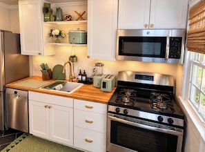Una cocina moderna con armarios blancos, electrodomésticos de acero inoxidable y encimera de madera.
