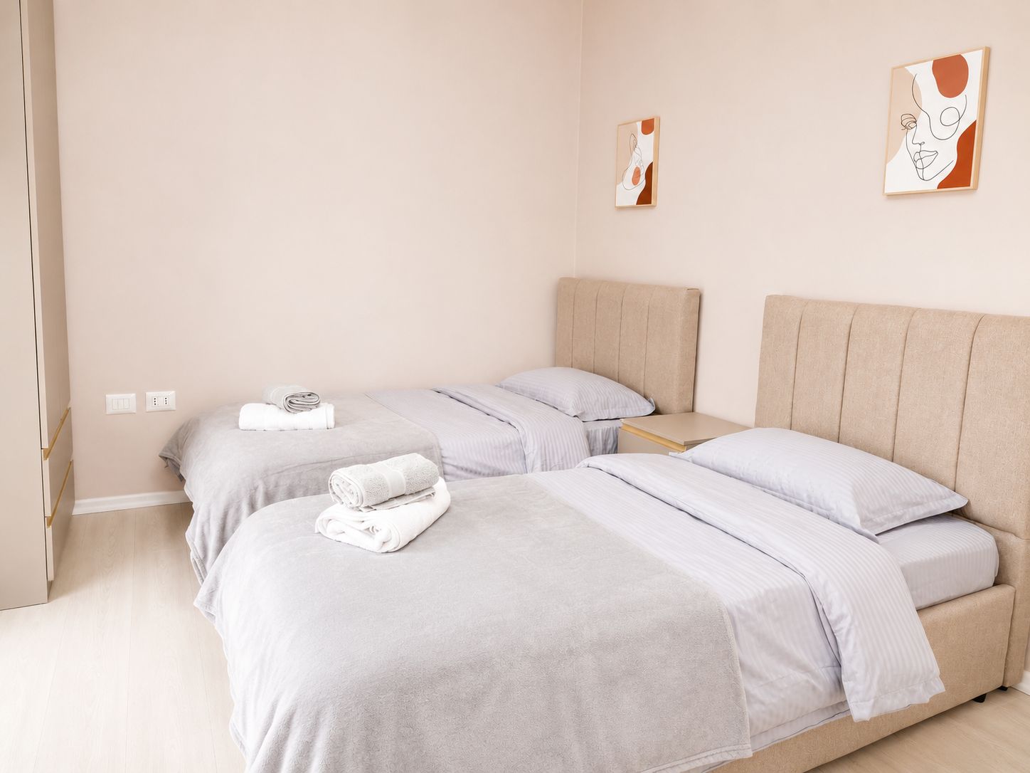 A hotel room with two beds, a bedside table, and artwork on the walls.